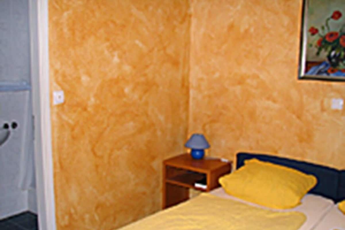 A bedroom with a bed, a nightstand, and a lamp.