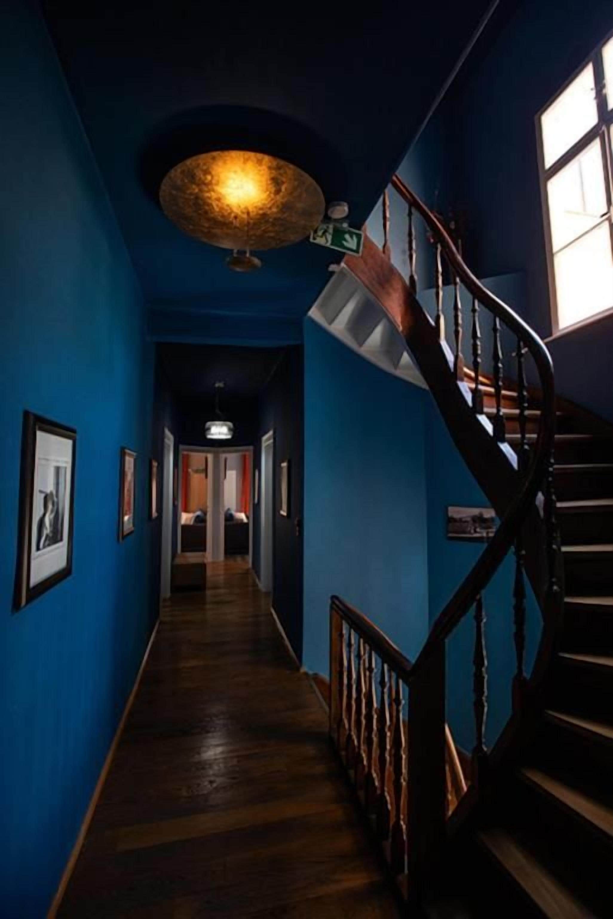 A hallway with a wooden staircase and a ceiling light fixture.