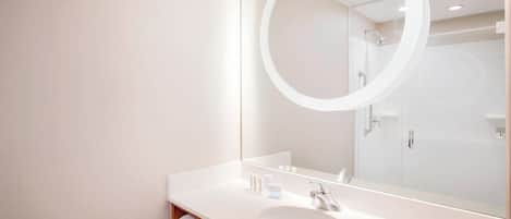 A modern bathroom with a large mirror, white sink, and a towel rack.