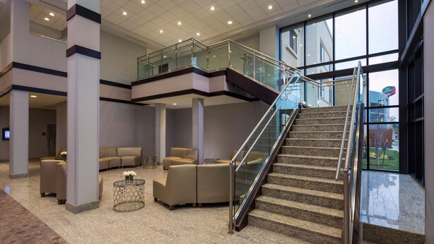 A spacious lobby with a glass staircase, comfortable seating areas, and a view of the outside. - Courtyard Marriott Lafayette (Lafayette)