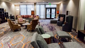 A hotel lobby with sofas, armchairs, a coffee table, and a bookshelf. - Courtyard Marriott Lafayette (Lafayette)