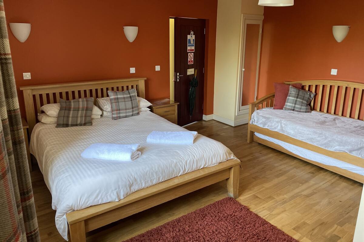 A bedroom with two wooden beds, a red rug, and a door with a coat hanging on it.