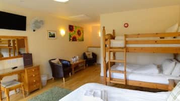 A compact hotel room with a bunk bed, a desk with a chair, a dresser, and a small table.