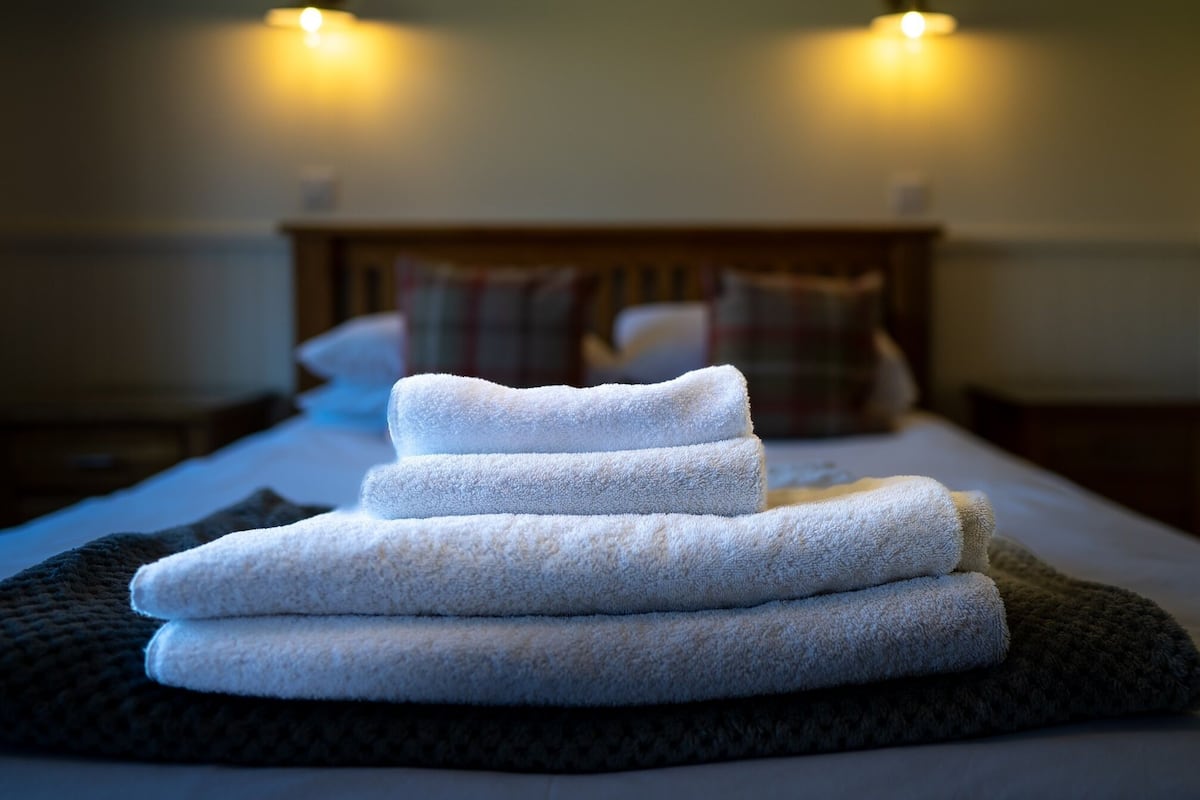 A neatly made bed with folded towels and a patterned blanket.