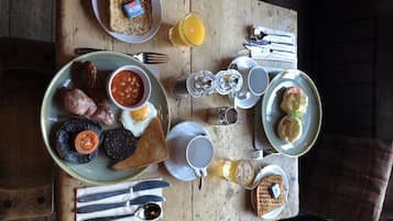 A breakfast table with toast, eggs, beans, sausages, and a variety of condiments.