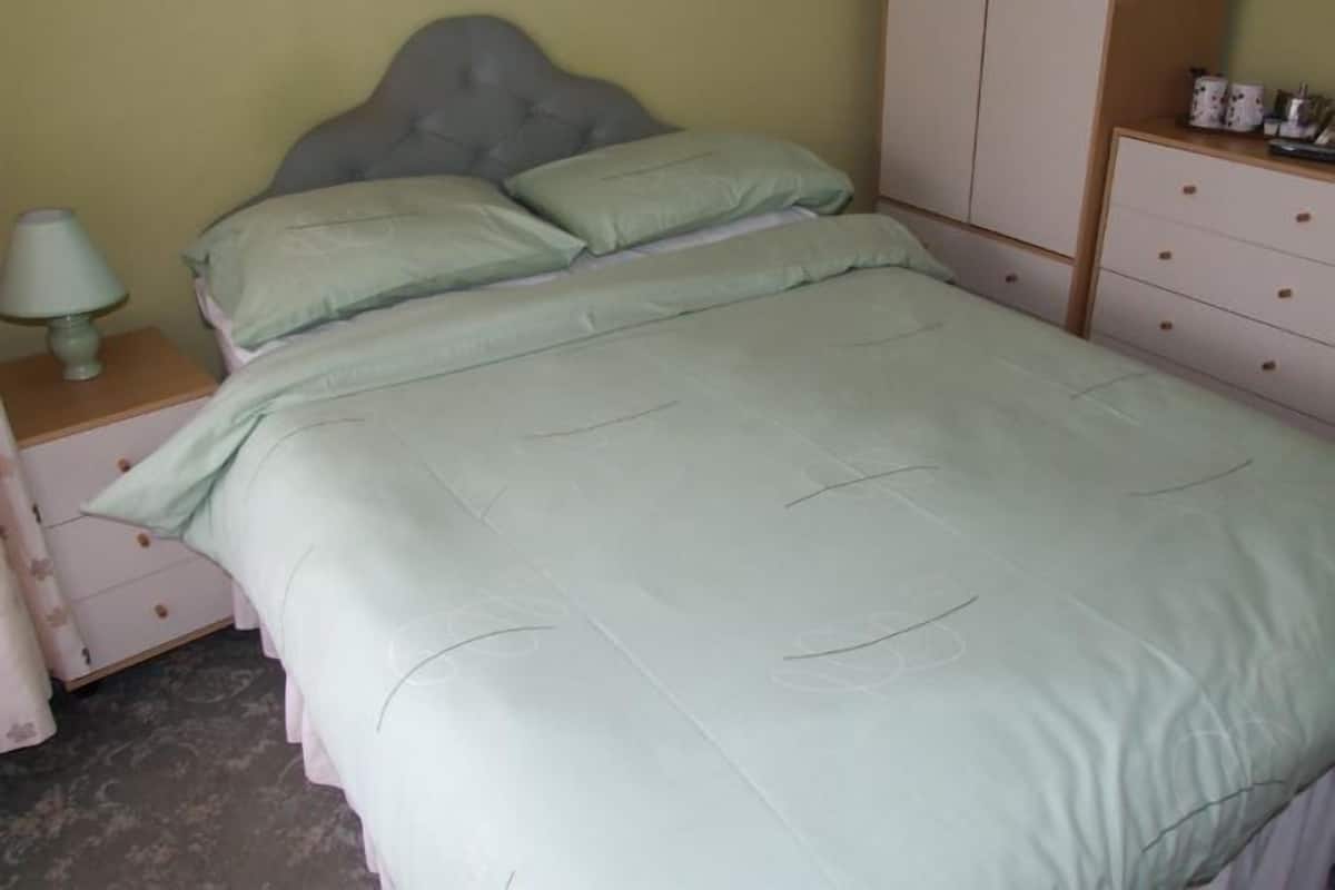 A bedroom with a bed, a nightstand, a dresser, and a wardrobe.