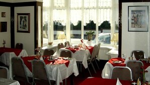 A dining area with tables set for two, white tablecloths, and chairs. - The Braedene Lodge B&B (Paignton)