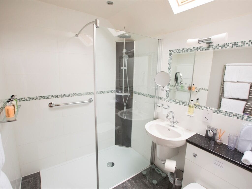 A modern bathroom with a glass-enclosed shower, a white sink, and a tiled backsplash.