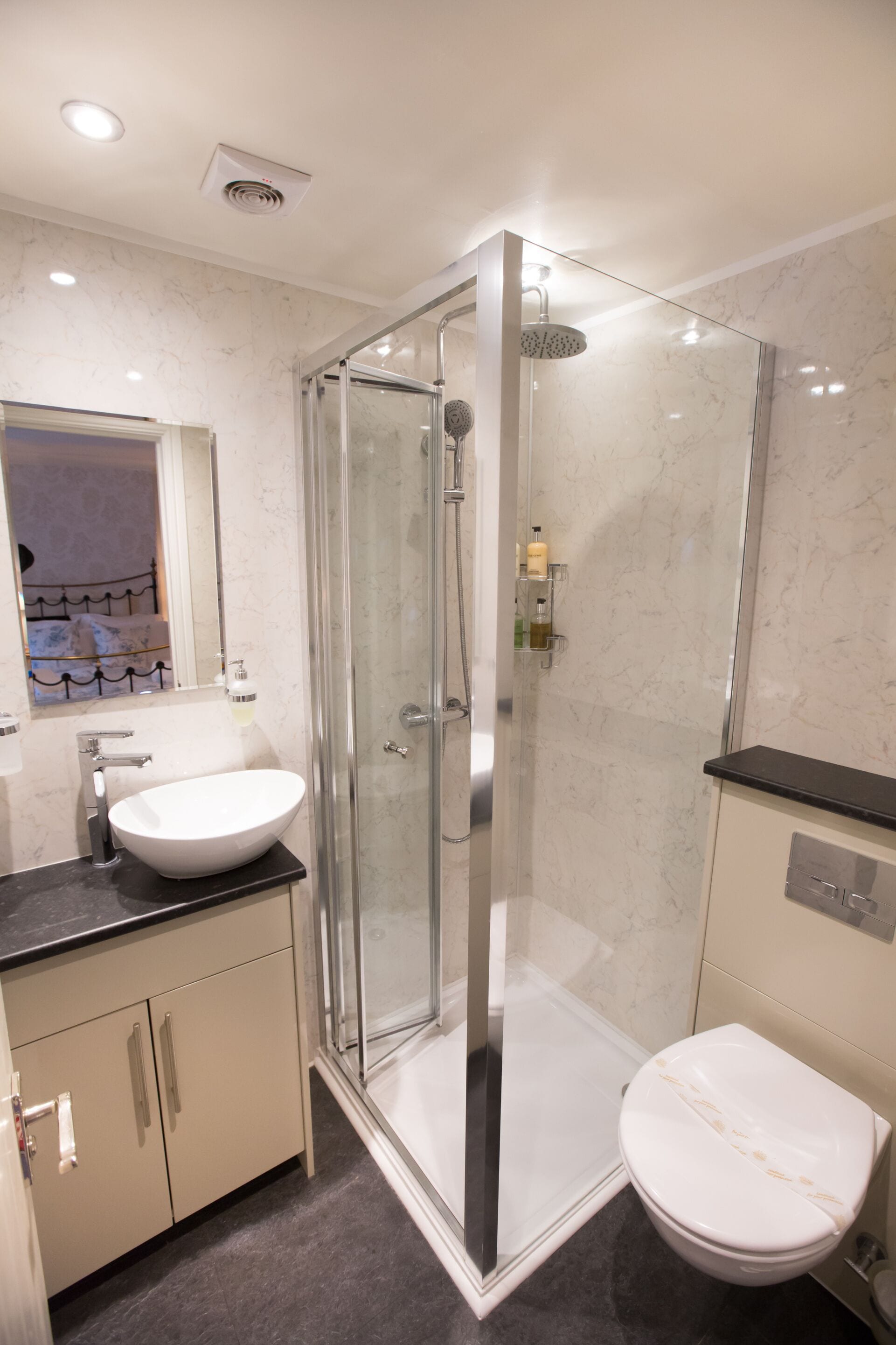 A modern bathroom with a glass-enclosed shower, a white sink, and a toilet.