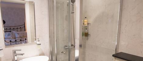 A modern bathroom with a glass-enclosed shower, a white sink, and a toilet.
