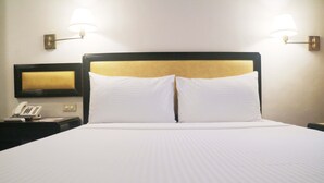 A hotel room with a large bed, two bedside lamps, a bedside telephone, and a flat-screen TV mounted on the wall. - Palm Hotel Manila (Manila)