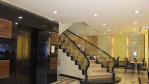 A lobby with a marble staircase, a reception desk, and a dining area with chairs and a table. - Palm Hotel Manila (Manila)