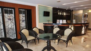 A reception area with a round table and chairs, a reception desk, and a wall-mounted TV. - Palm Hotel Manila (Manila)