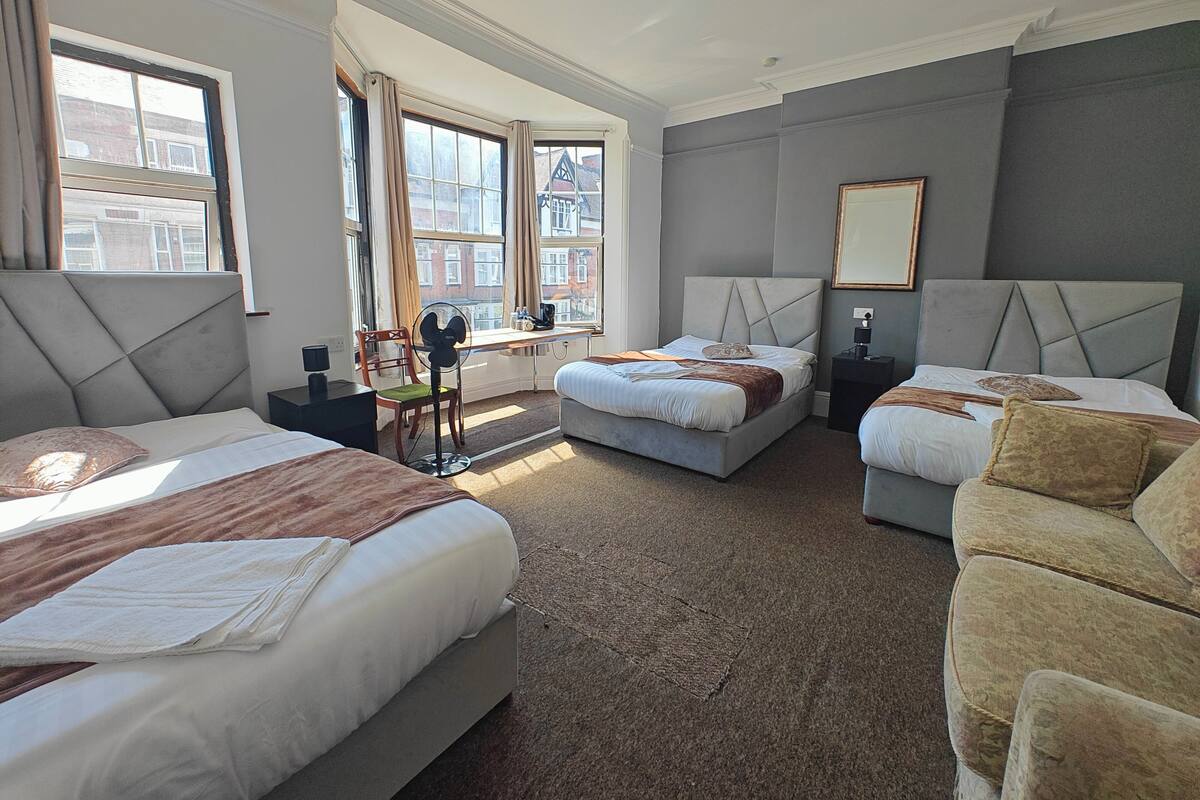 A hotel room with two beds, a desk, a chair, and a large window.