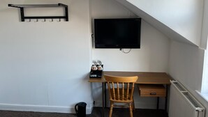 A small, well-lit room with a desk, chair, and a mounted TV. - Campbell's Guest House (Leicester)