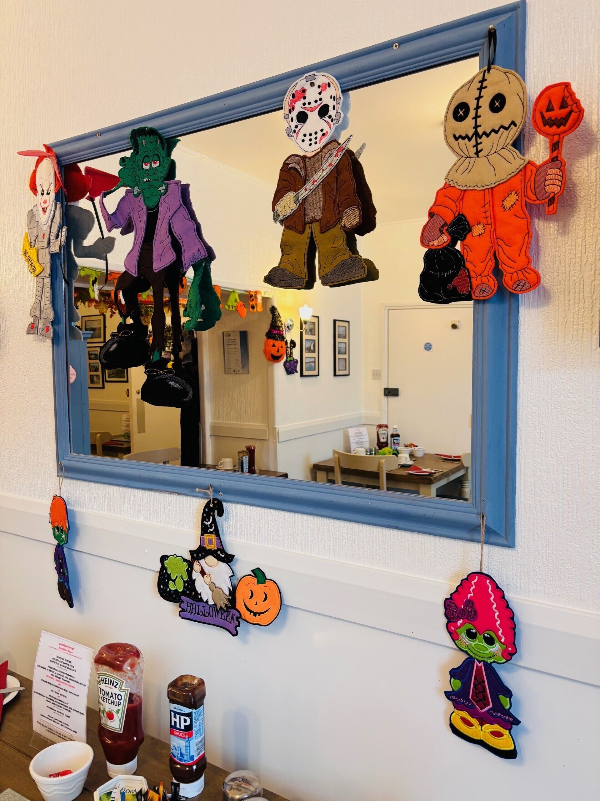 Ein Spiegel mit Halloween-Dekoration, darunter ein Kürbis, ein Geist und eine Figur mit einem Messer.