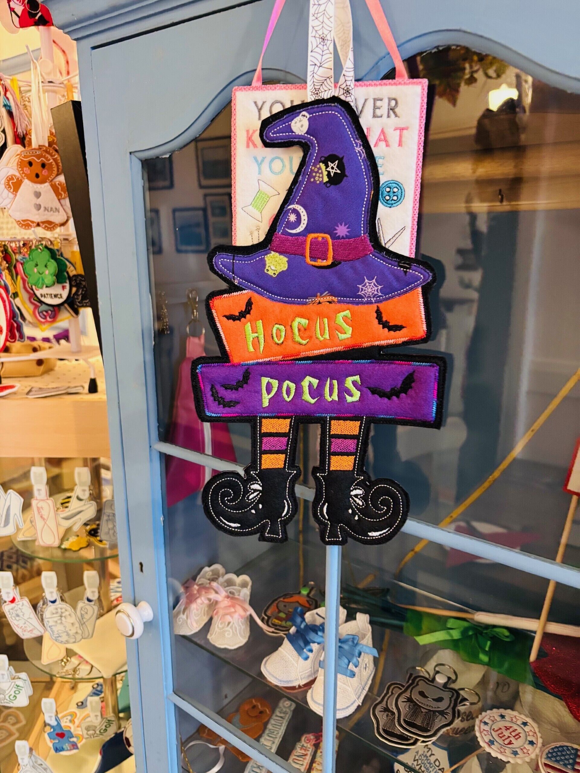 Eine Schaufensterpuppe mit Hexenhut-Dekoration, beschriftet mit „Hocus Pocus“ und einem Schild mit der Aufschrift „Gern geschehen“.
