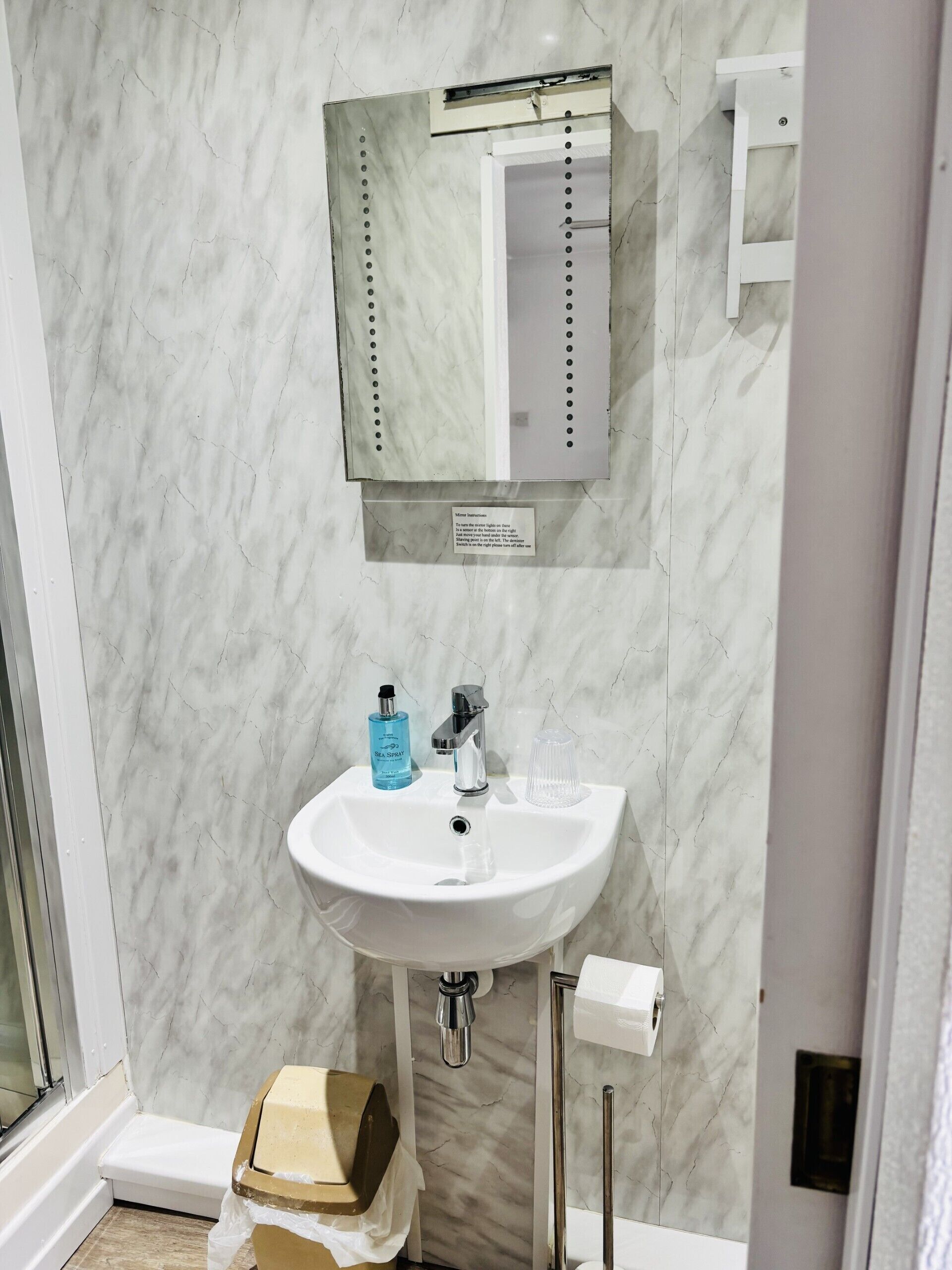 Ein Badezimmer mit einem weißen Waschbecken, einem Spiegel und einem Handtuchspender.