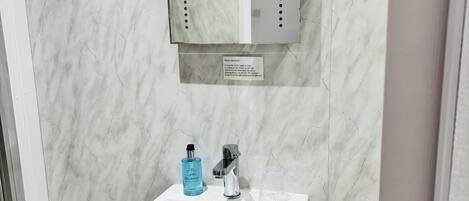 Ein Badezimmer mit einem weißen Waschbecken, einem Spiegel und einem Handtuchspender.
