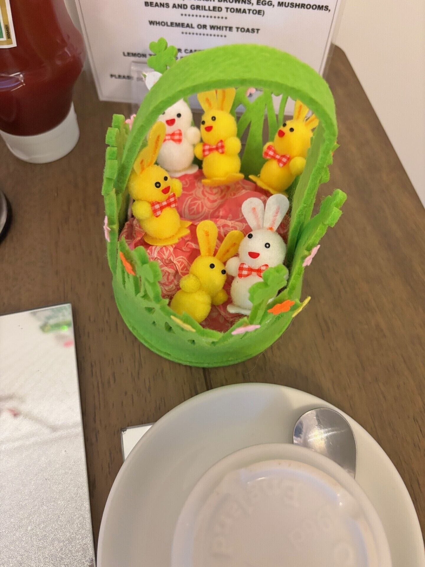 Une table avec un panier contenant des lapins en feutrine et une assiette blanche avec une cuillère.