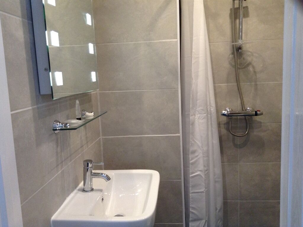 A bathroom with a white sink, a mirror, and a shower with a curtain.