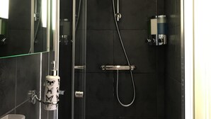 A modern bathroom with a glass-enclosed shower, a white sink, and a mirror. - Cassandra Guest House (Plymouth)
