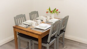 A dining table set with white plates, bowls, and cutlery, accompanied by a vase of tulips. - Castle Park Hotel (Leicester)