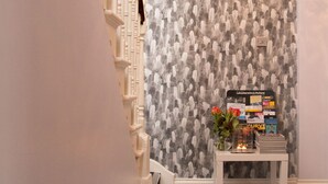 A staircase with a patterned wallpaper, a small table with a vase and candles, and a hanging light fixture. - Castle Park Hotel (Leicester)