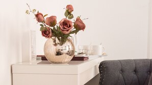 A white desk with a vase of pink roses, a white mug, and a book. - Castle Park Hotel (Leicester)