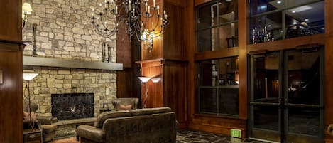 A spacious lobby with a stone fireplace, leather sofas, and a chandelier.