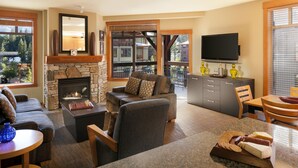 Una sala de estar con chimenea de piedra, un sofá, un televisor y un comedor con mesa y sillas.