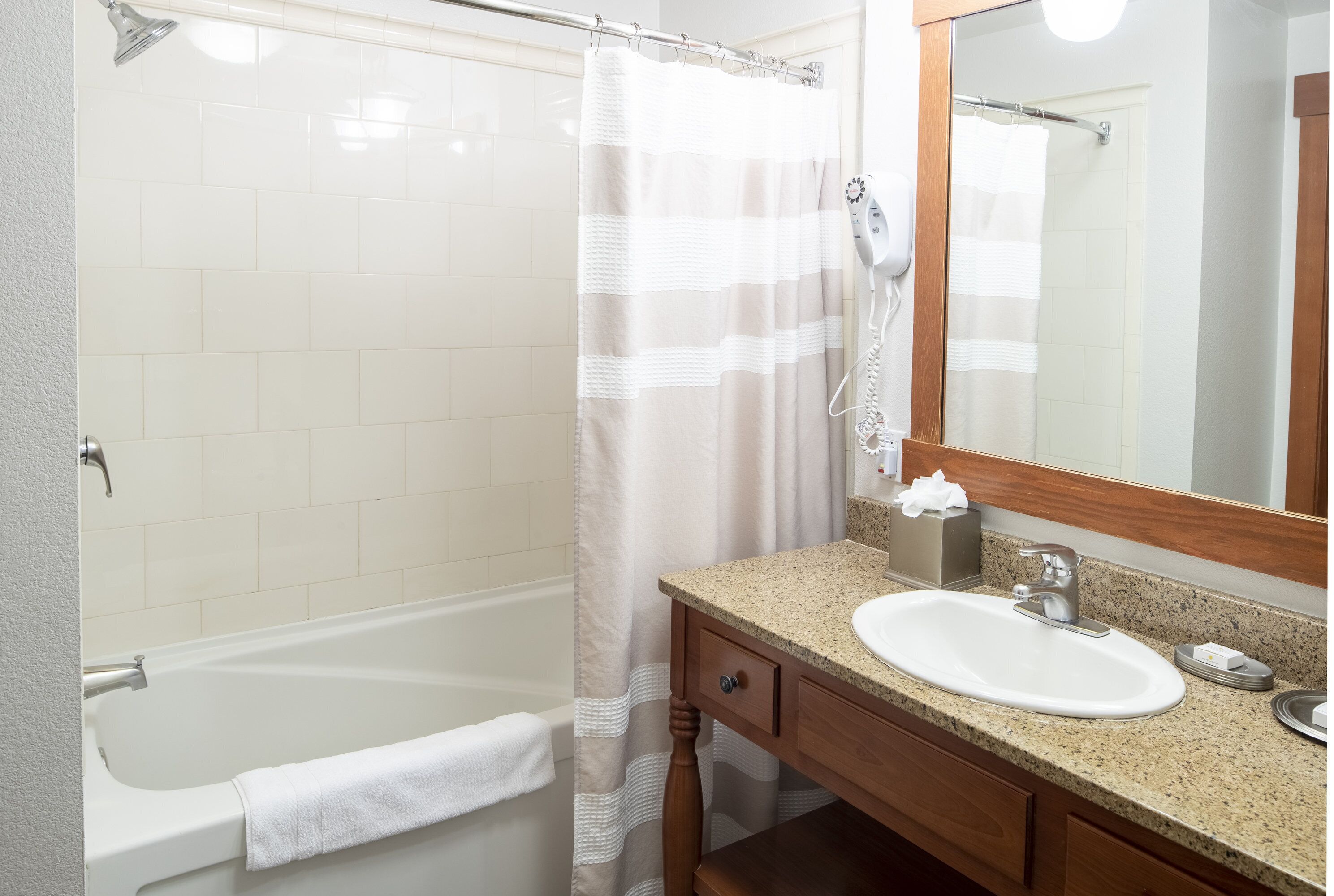 A bathroom with a bathtub, a sink, a mirror, and a shower curtain.