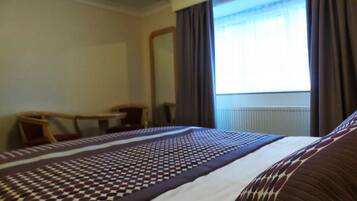 Une chambre d’hôtel avec un lit, un bureau et une chaise.