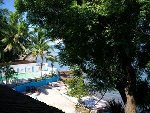 A beachfront property with a pool, lounge chairs, and a view of the sea. - Las Flores Country & Beachside Hotel (Catmon)