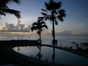 A swimming pool with a view of the sea and palm trees. - Las Flores Country & Beachside Hotel (Catmon)