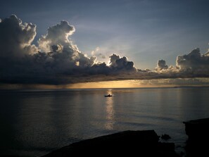 A calm sea with a boat in the distance, under a cloudy sky. - Las Flores Country & Beachside Hotel (Catmon)