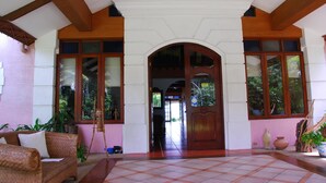 Un hall d’entrée spacieux, doté d’un sol carrelé, d’un banc en bois et d’une grande porte en arc donnant sur un couloir.