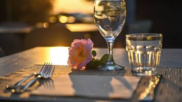 A table set with a wine glass, a water glass, and a rose.