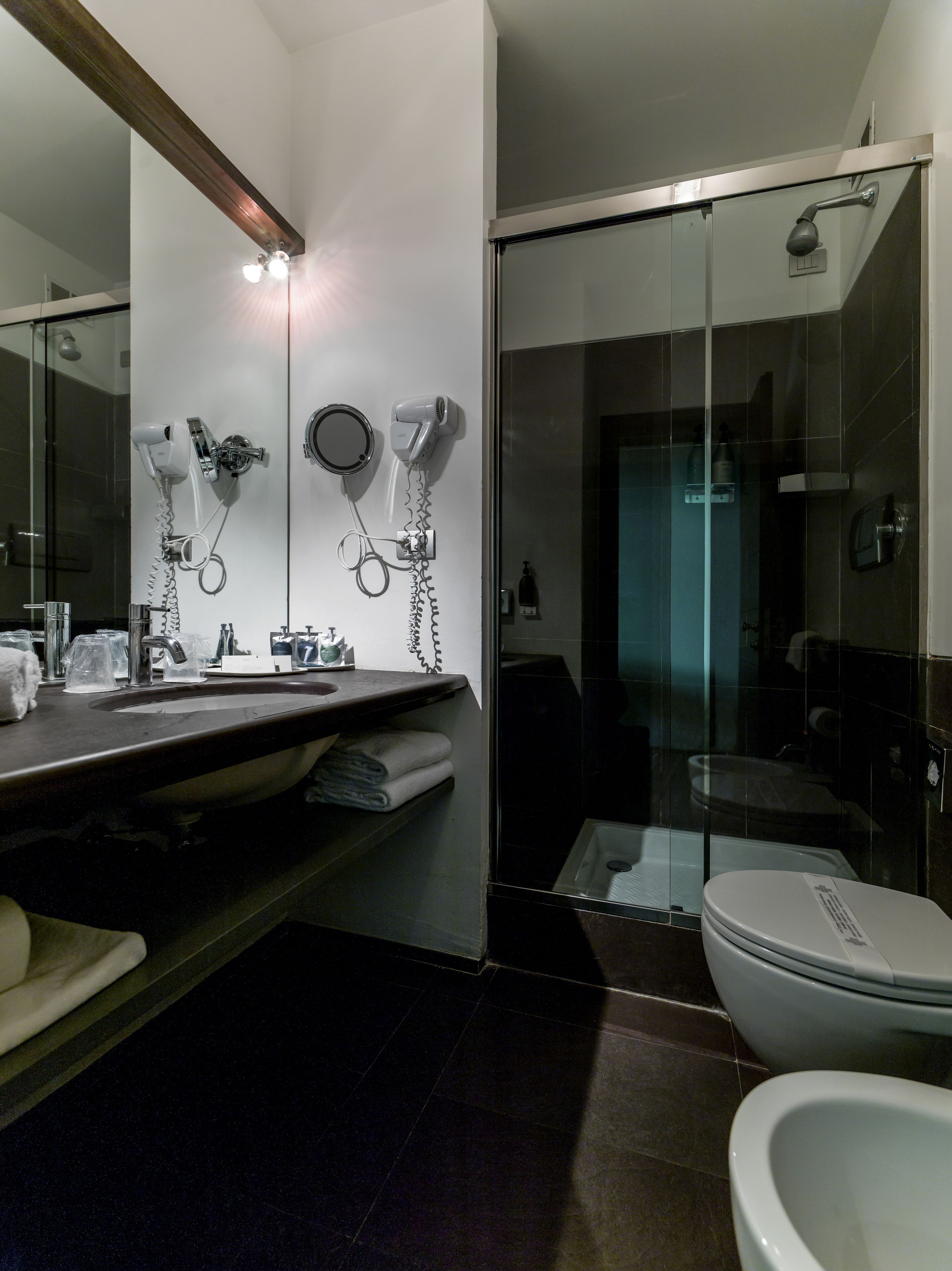A modern bathroom with a glass shower enclosure, a vanity with a sink and mirror, and a toilet.