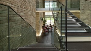 A modern interior with a glass staircase, brick walls, and a seating area with tables and chairs. - Best Western Hotel Green City (Parma)