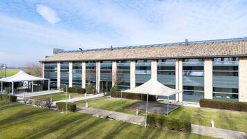 Un bâtiment moderne doté de grandes fenêtres, d’un espace extérieur couvert et d’une pelouse bien entretenue.