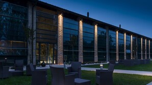 A modern building with large glass windows and outdoor seating areas. - Best Western Hotel Green City (Parma)