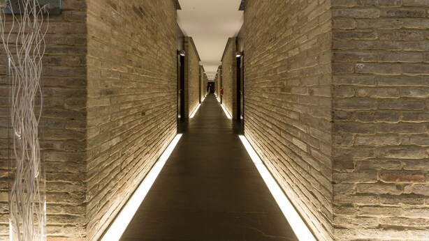 A long, narrow hallway with brick walls and a sign indicating a reception and breakfast room. - Best Western Hotel Green City (Parma)