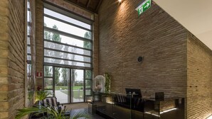 A reception area with a glass desk, a clock on the wall, and a green exit sign. - Best Western Hotel Green City (Parma)