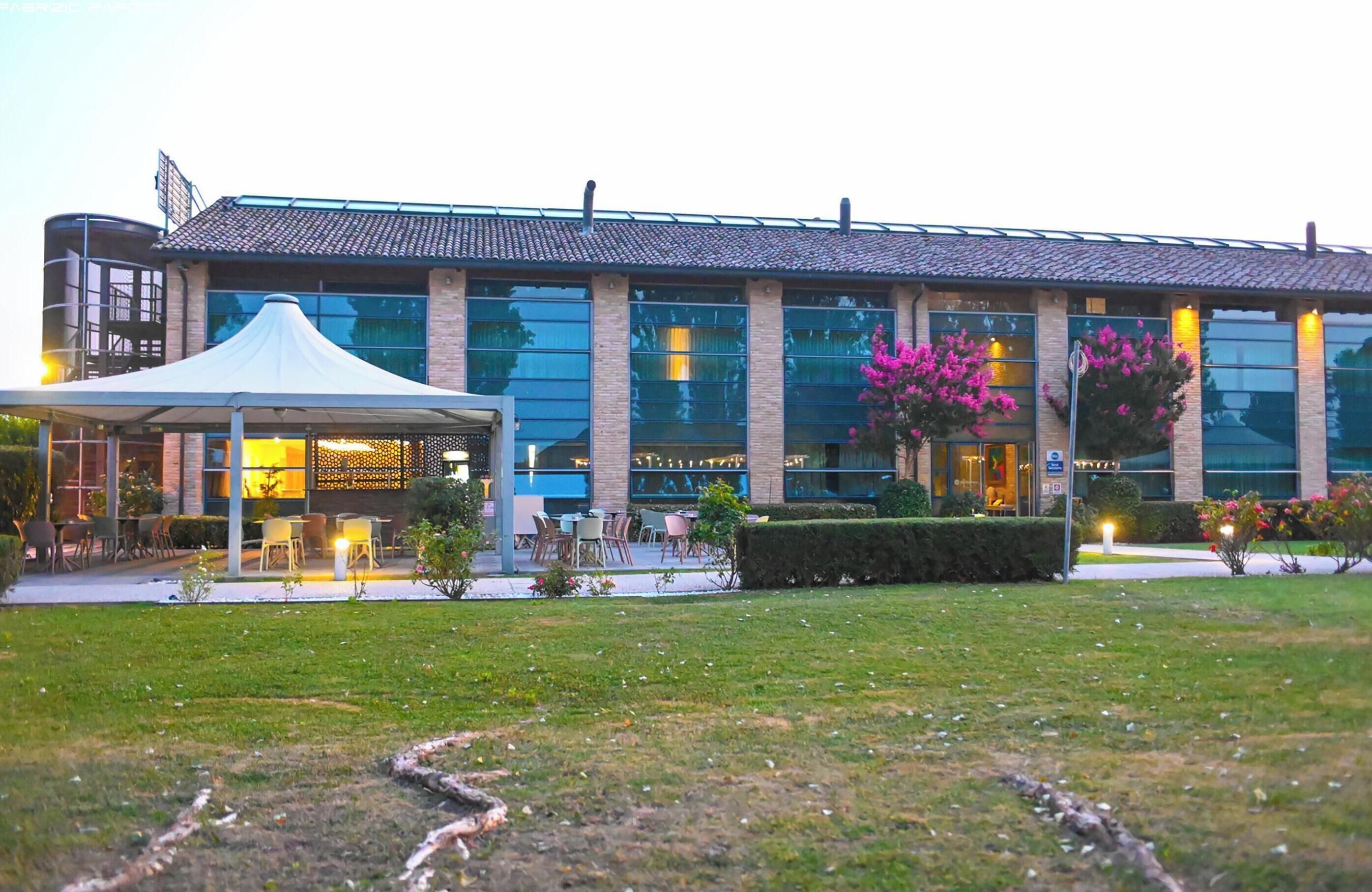 Un edificio moderno con facciata in vetro, area salotto esterna e patio coperto.