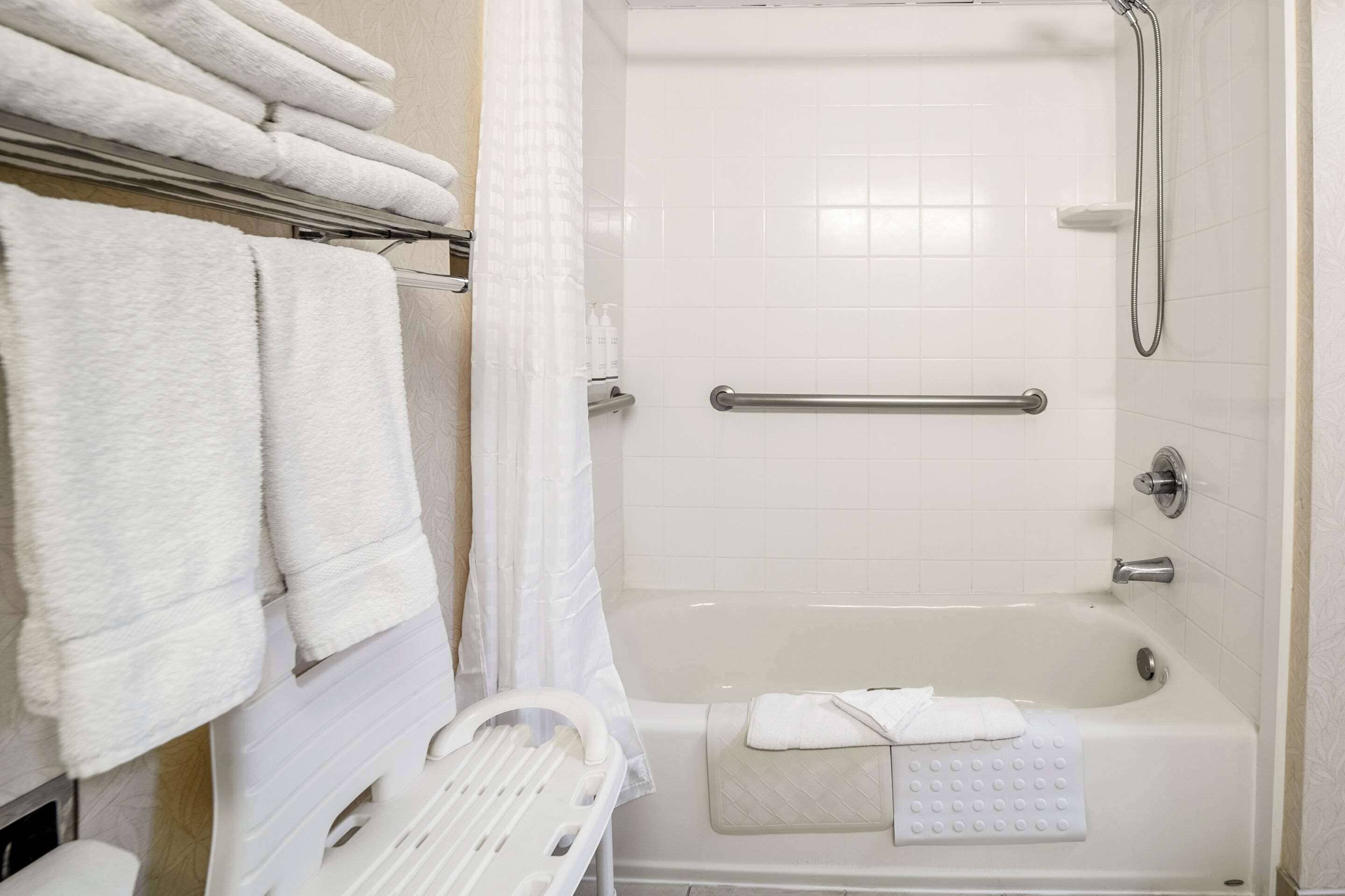 A bathroom with a bathtub, a shower, and a towel rack with folded towels.