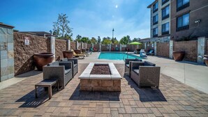A poolside area with lounge chairs, a fire pit, and a swimming pool. - Country Inn & Suites by Radisson, Ontario at Ontario Mills, CA (Ontario)