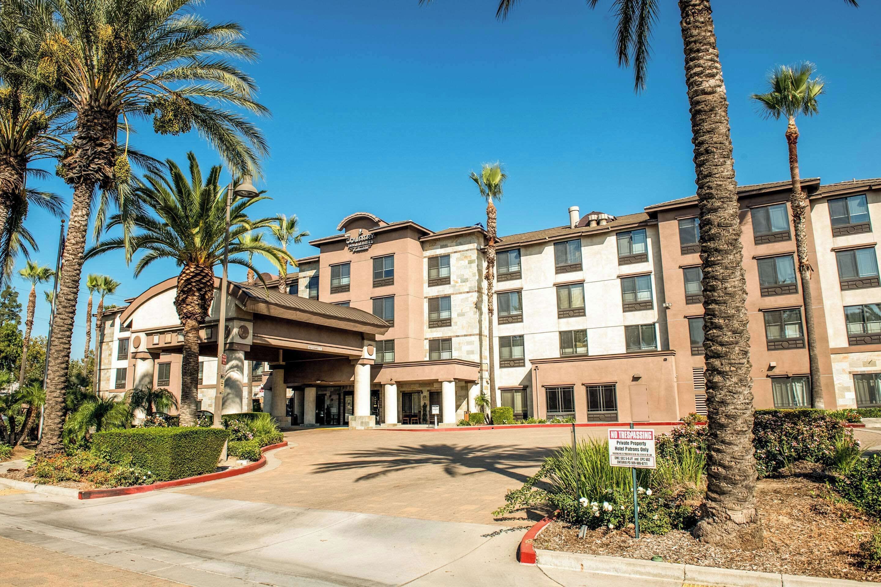 A hotel with a central entrance, palm trees, and a 'No Trespassing' sign.