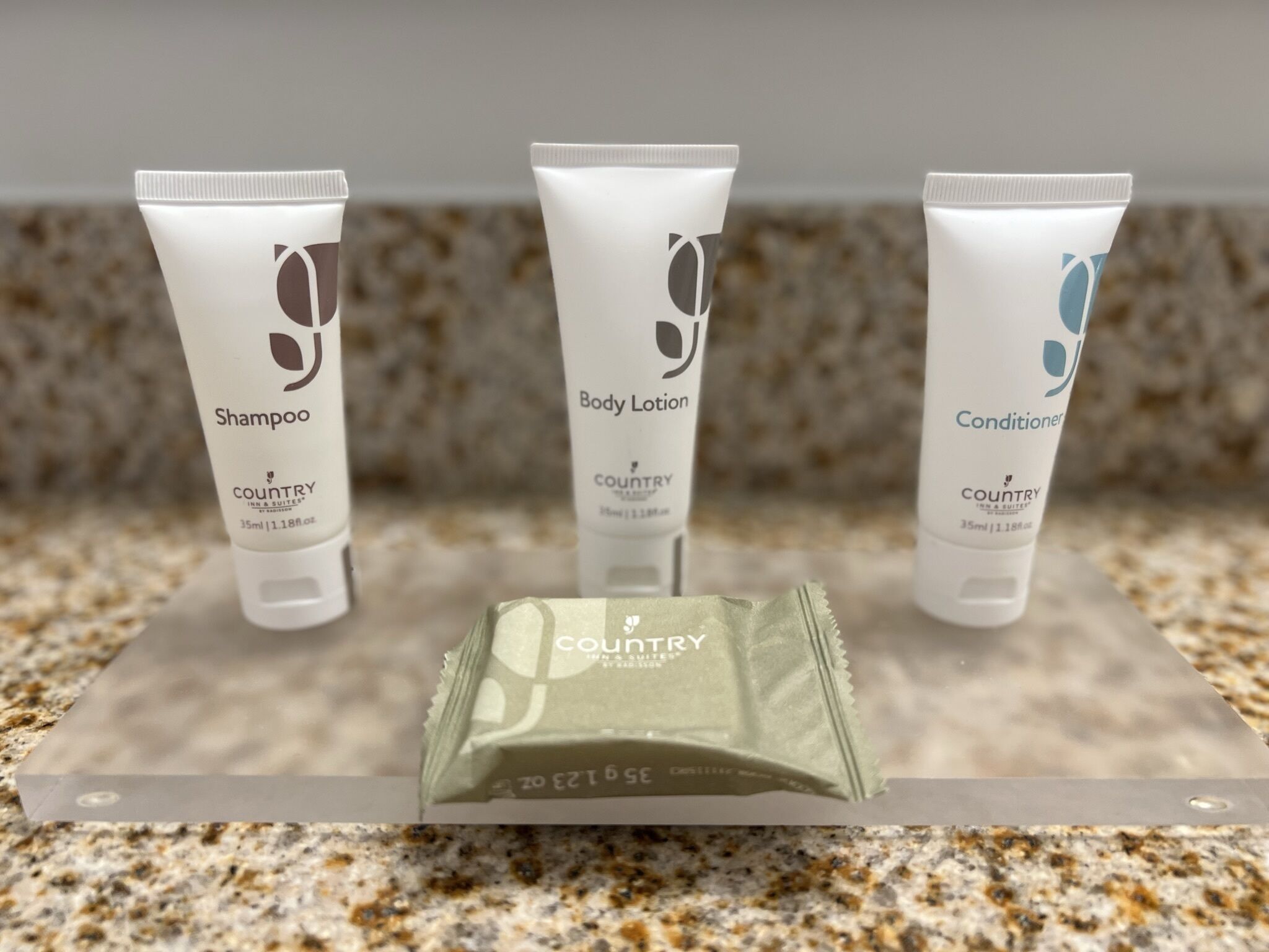 Three toiletries: a shampoo, a body lotion, and a conditioner, each labeled 'COUNTRY INN & SUITES'.
