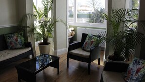 Una sala de estar acogedora con un sofá, sillones, una mesa de centro y plantas en macetas.
